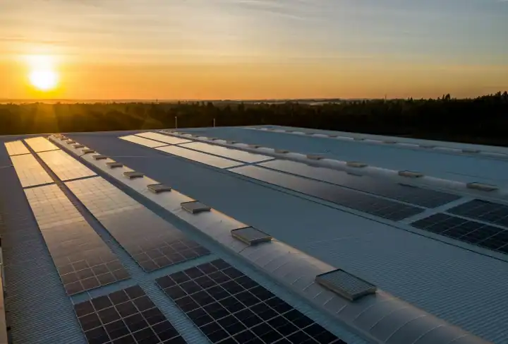 Solaranlage und Windräder bei Sonnenuntergang am Meer