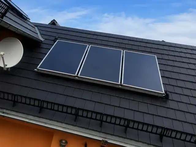 Solarkollektoren auf Hausdach mit Satellitenschüssel