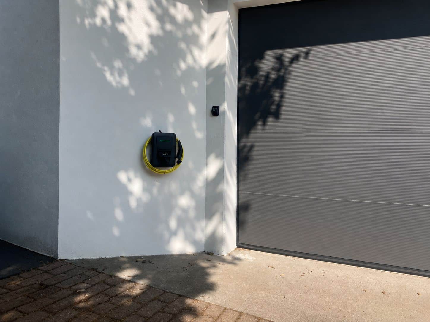 Wallbox mit Ladekabel neben moderner Garage